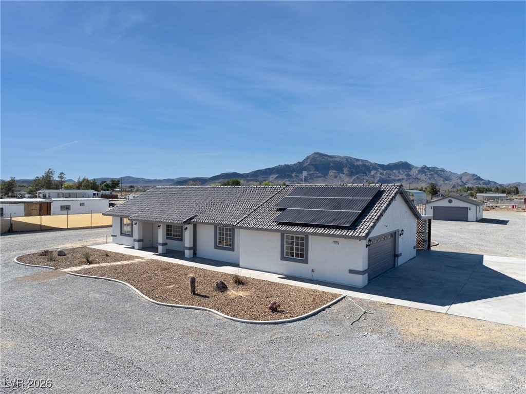 2420 Tough Boy Road Pahrump, NV 89060 - Photo 46 of 54 Single story home featuring a mountain view, concrete driveway, roof mounted solar panels, stucco siding, and a garage