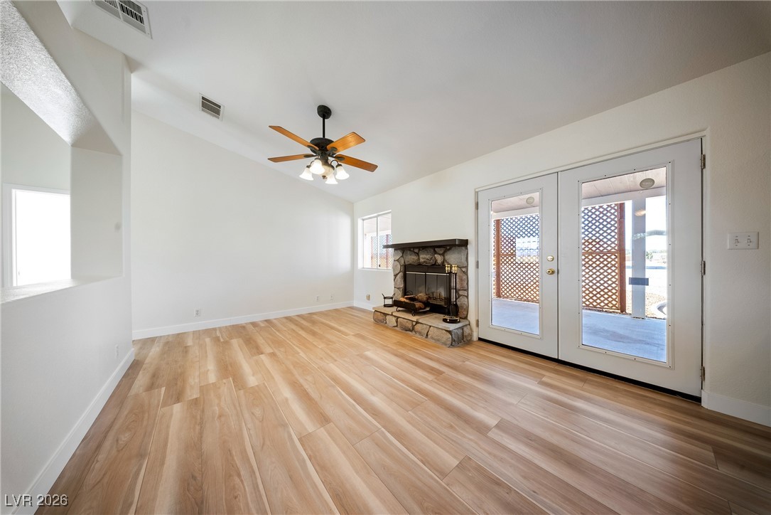 2420 Tough Boy Road Pahrump, NV 89060 - Photo 9 of 54 Unfurnished living room with french doors, lofted ceiling, wood finished floors, ceiling fan, and a fireplace