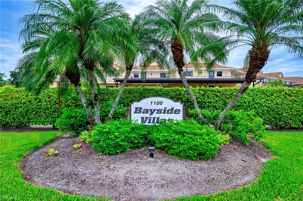 a sign that is sitting in front of a house with a garden