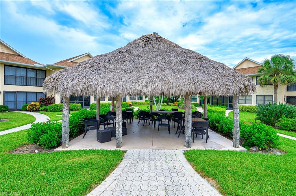 1100 9th Street South, Unit E101 Naples, FL 34102 - Photo 18 of 35 a view of a patio with table and chairs under an umbrella