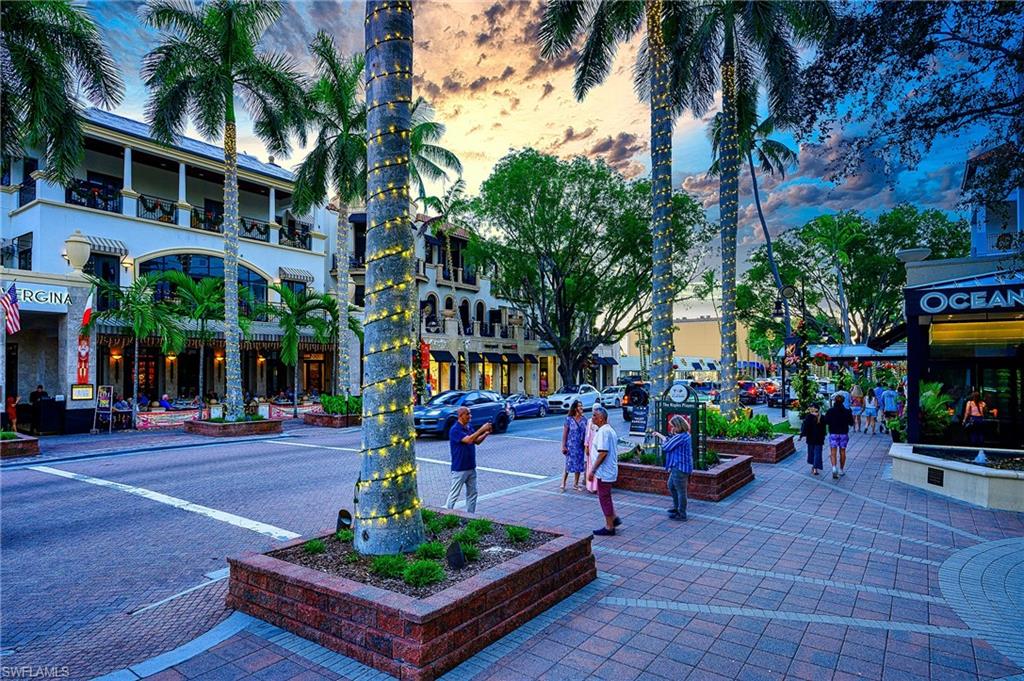 1100 9th Street South, Unit E101 Naples, FL 34102 - Photo 27 of 35 a view of a patio with a table and chairs under an umbrella