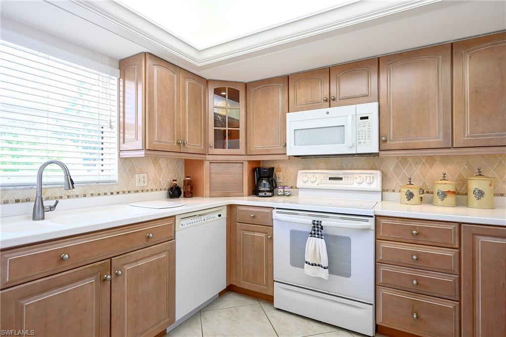 1100 9th Street South, Unit E101 Naples, FL 34102 - Photo 4 of 35 a kitchen with cabinets appliances a sink and a window