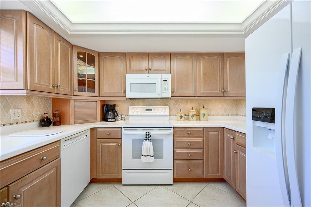 1100 9th Street South, Unit E101 Naples, FL 34102 - Photo 5 of 35 a kitchen with stainless steel appliances granite countertop a sink and dishwasher a stove top oven with white cabinets