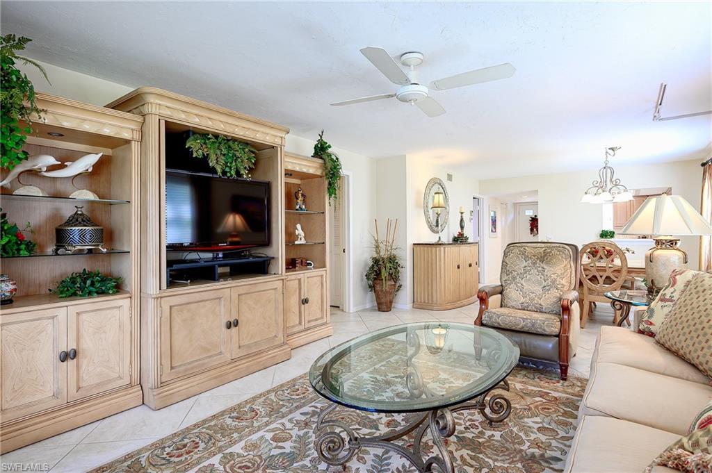 1100 9th Street South, Unit E101 Naples, FL 34102 - Photo 8 of 35 a living room with furniture a flat screen tv and a rug