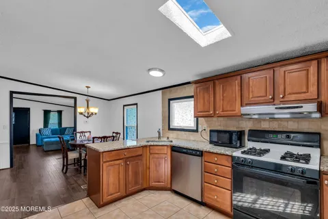 a kitchen with stainless steel appliances granite countertop a stove a sink dishwasher and a microwave oven with wooden floor