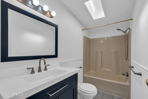 a bathroom with a sink a toilet a mirror and shower