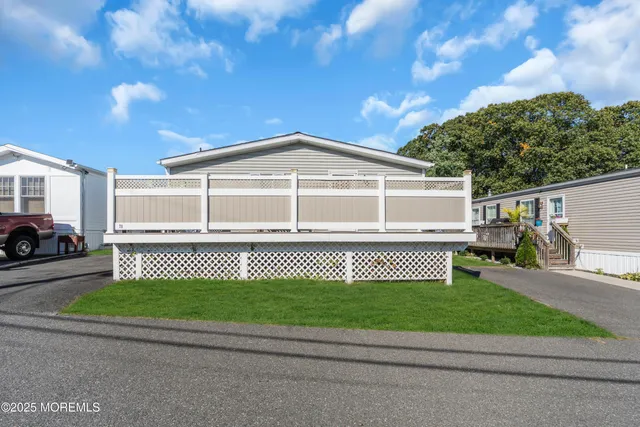 a view of a white house with a big yard and large trees