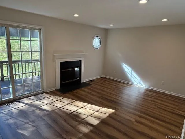 a view of empty room with wooden floor and fireplace