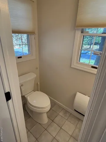 a white toilet sitting next to a window in a bathroom