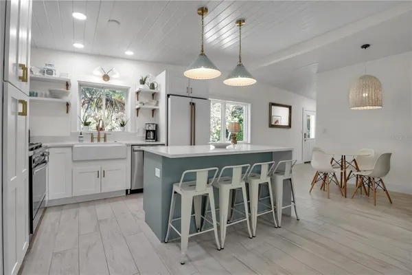 a kitchen with a dining table chairs cabinets wooden floor and appliances