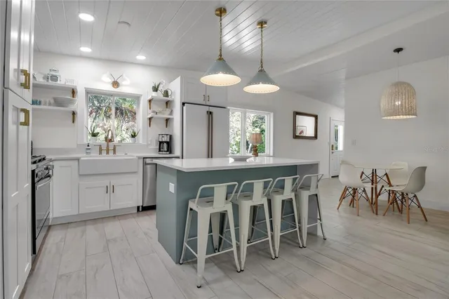 a kitchen with a dining table chairs cabinets wooden floor and appliances