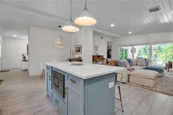 a living room with stainless steel appliances furniture a chandelier and a view of kitchen
