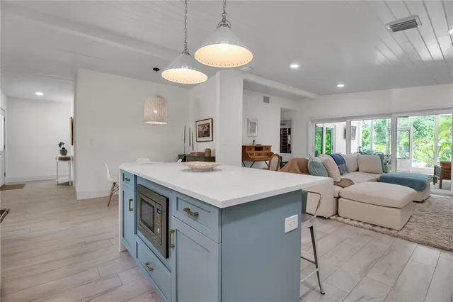 a living room with stainless steel appliances furniture a chandelier and a view of kitchen