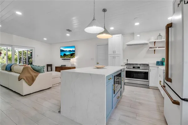 a large white kitchen with stainless steel appliances a stove a sink a oven and a refrigerator with wooden floor