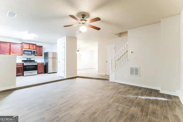 a view of a kitchen with a sink cabinet a ceiling fan and wooden floor