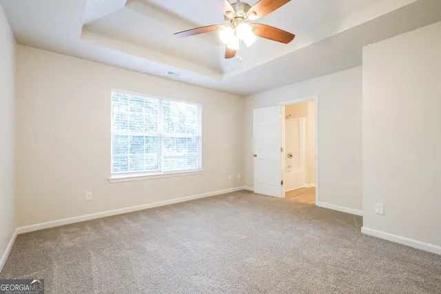 an empty room with windows and fan