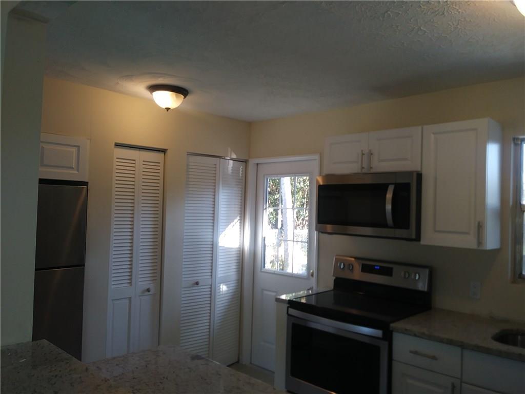 1474 Southwest Del Rio Boulevard Port St. Lucie, FL 34953 - Photo 6 of 9 a kitchen with a refrigerator and a stove top oven