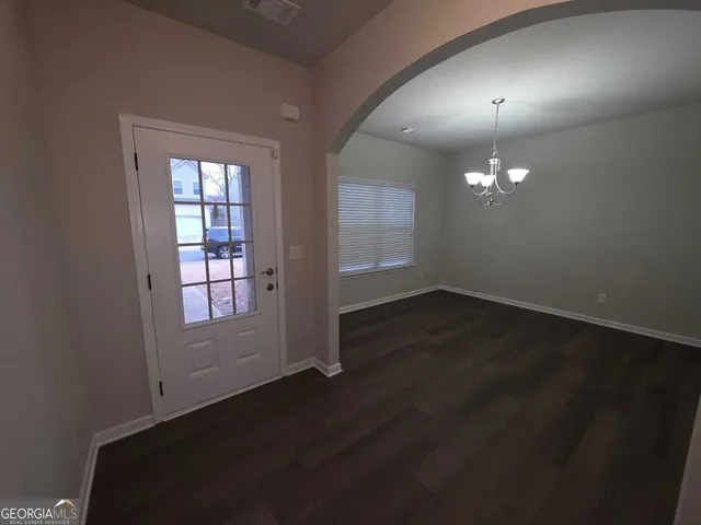 an empty room with wooden floor chandelier and windows