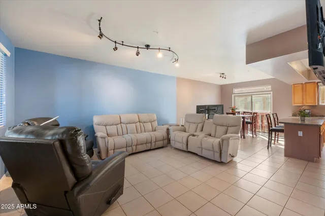 a living room with furniture and a dining table with kitchen appliances