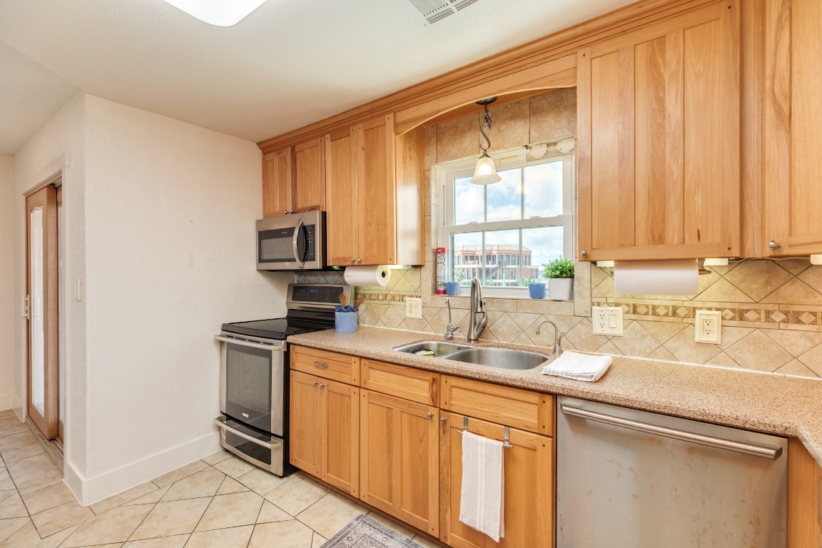 411 Sailfish Lane, Unit 101 Freeport, TX 77541 - Photo 18 of 40 a kitchen with stainless steel appliances granite countertop a sink a stove and a refrigerator with wooden cabinets