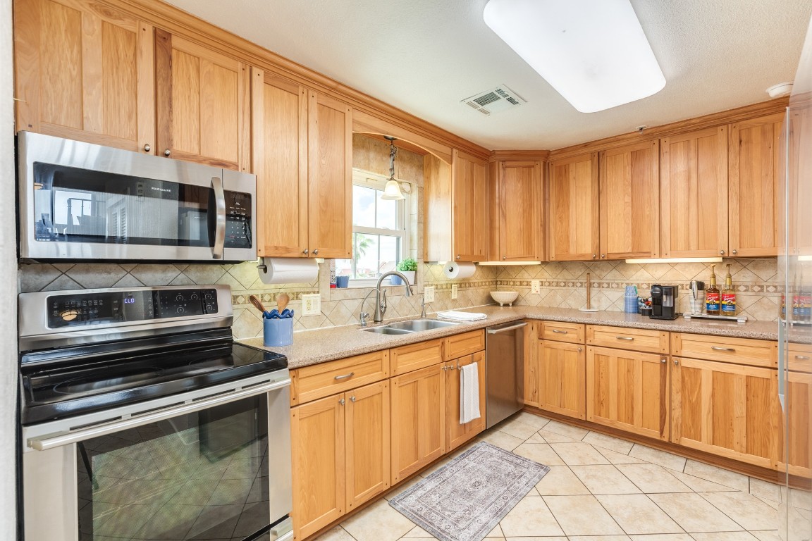 411 Sailfish Lane, Unit 101 Freeport, TX 77541 - Photo 6 of 40 a kitchen with stainless steel appliances granite countertop a stove microwave and sink