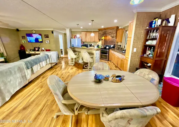 a living room with stainless steel appliances furniture a rug and a kitchen view