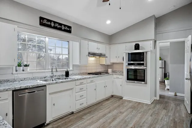 a kitchen with stainless steel appliances granite countertop a sink a stove a refrigerator and cabinets