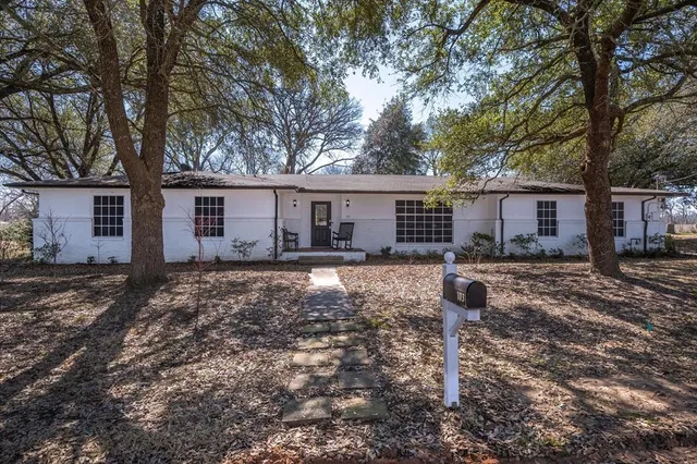 a front view of a house with a yard tree and wooden fence