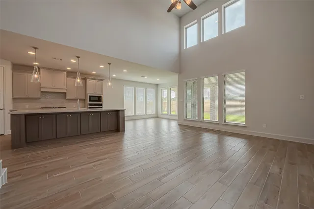 a view of an empty room with wooden floor and kitchen