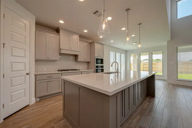 a kitchen with kitchen island a sink and a stove with wooden floor