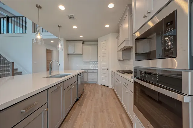 a large kitchen with stainless steel appliances granite countertop a lot of counter space and wooden floor