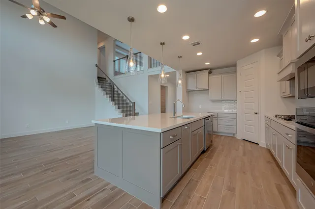 a large kitchen with stainless steel appliances granite countertop a lot of counter space and wooden floors
