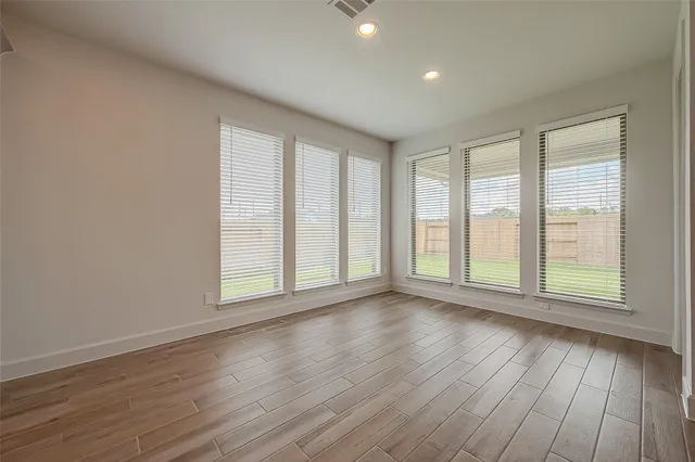a view of an empty room with wooden floor and a window