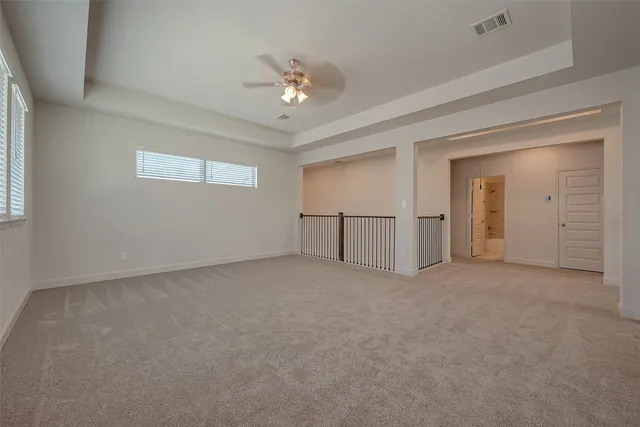 a view of an empty room with chandelier fan and fire place