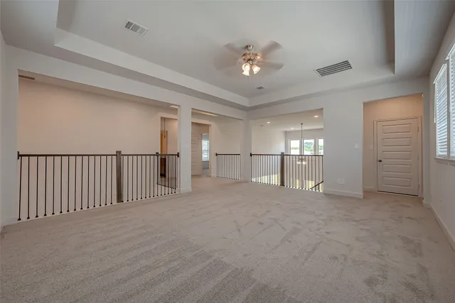 a view of an empty room with a chandelier fan
