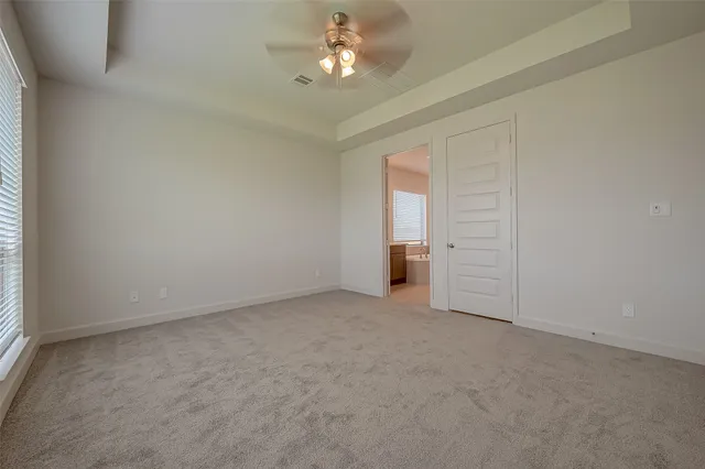an empty room with chandelier fan and windows