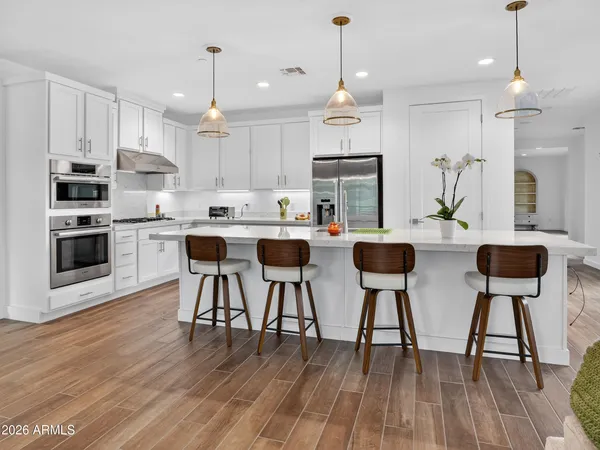 a kitchen with stainless steel appliances kitchen island wooden floor and white cabinets
