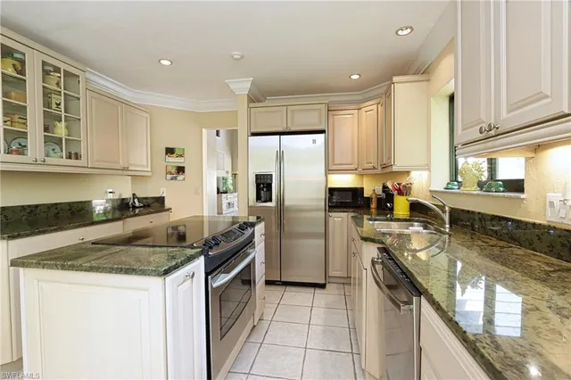 a kitchen with granite countertop kitchen island stainless steel appliances a refrigerator a sink a stove a counter space and cabinets