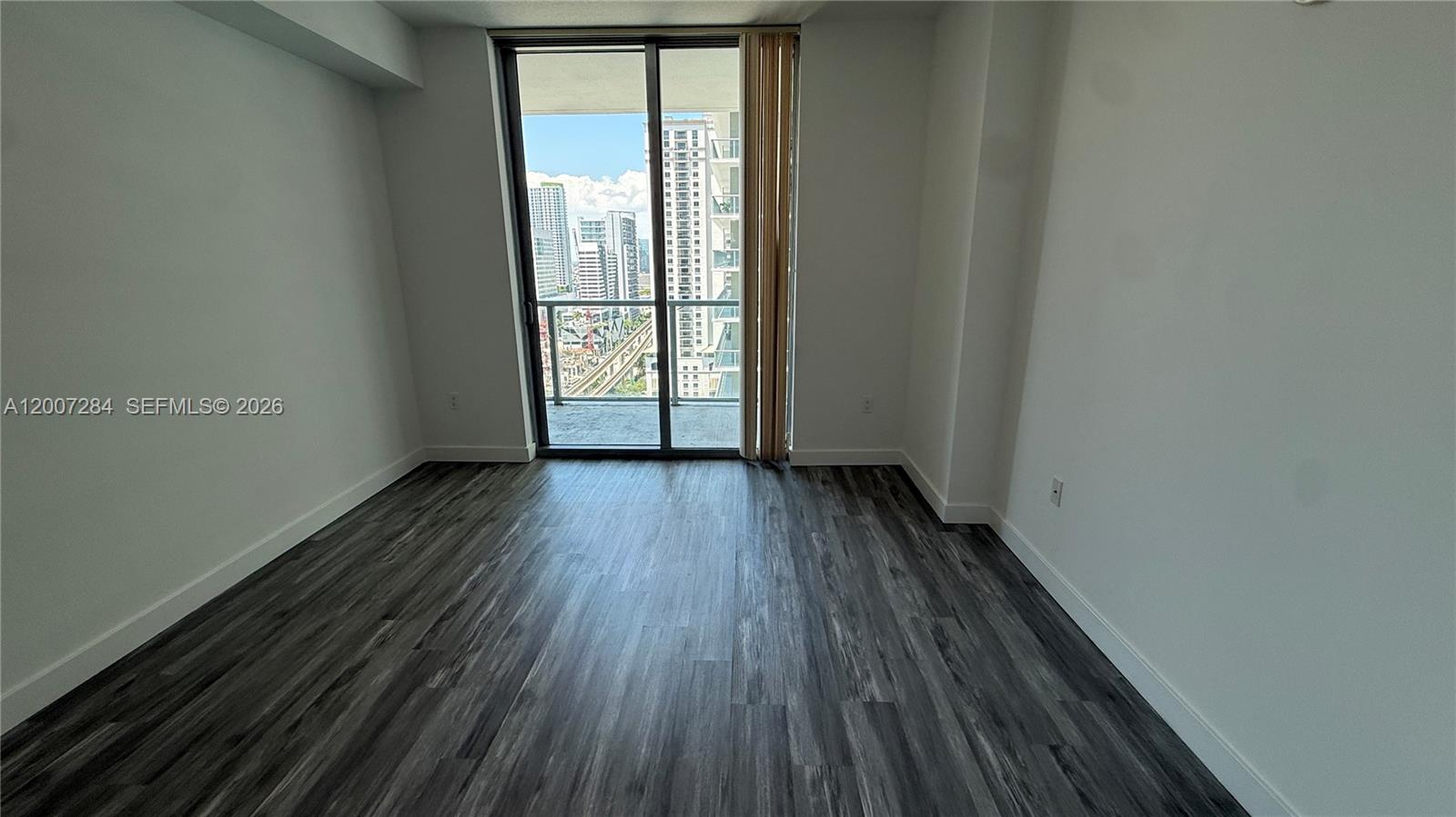 79 Southwest 12th Street, Unit 2509S Miami, FL 33130 - Photo 13 of 27 a view of an empty room with wooden floor and a window