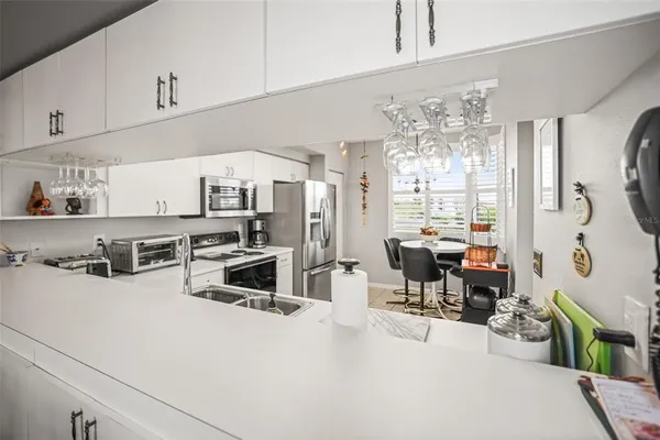 a kitchen with stainless steel appliances a stove a refrigerator a sink dishwasher with a dining table and chairs