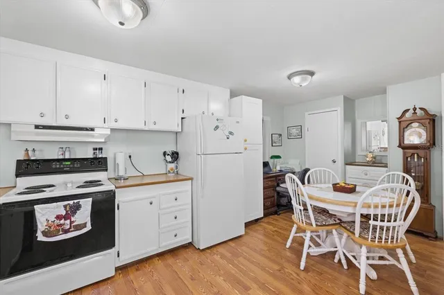 a kitchen with stainless steel appliances a dining table chairs and wooden floor