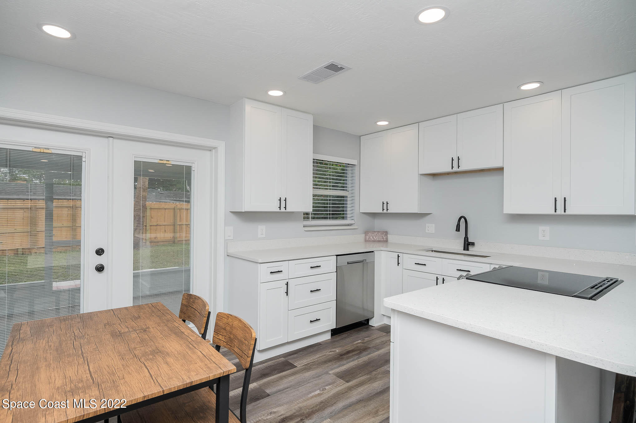 1026 Macco Road Cocoa, FL 32927 - Photo 7 of 20 a kitchen with a stove a sink a refrigerator and white cabinets with wooden floor