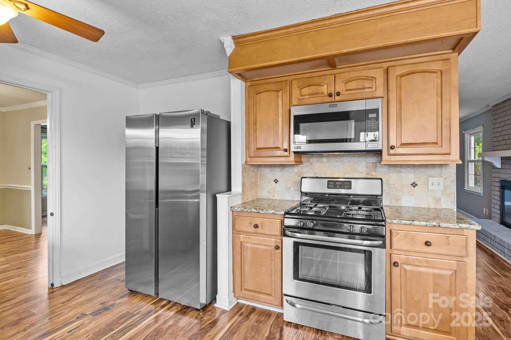 101 Wynnchester Road Gastonia, NC 28056 - Photo 14 of 46 a kitchen with granite countertop wooden cabinets stainless steel appliances and a wooden floor