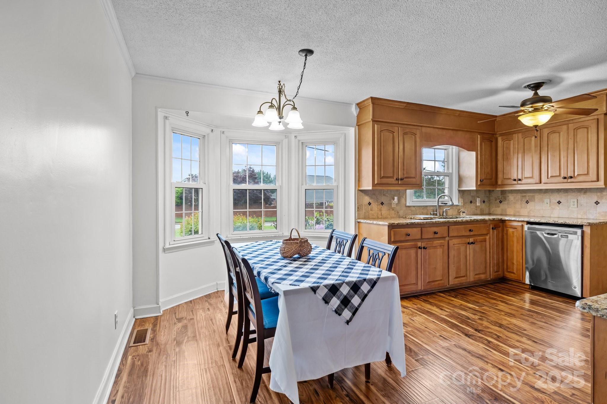 101 Wynnchester Road Gastonia, NC 28056 - Photo 15 of 46 a kitchen with granite countertop a stove a sink dishwasher a dining table and chairs with wooden floor