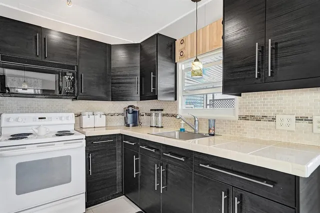 a kitchen with stainless steel appliances a sink dishwasher stove and white cabinets