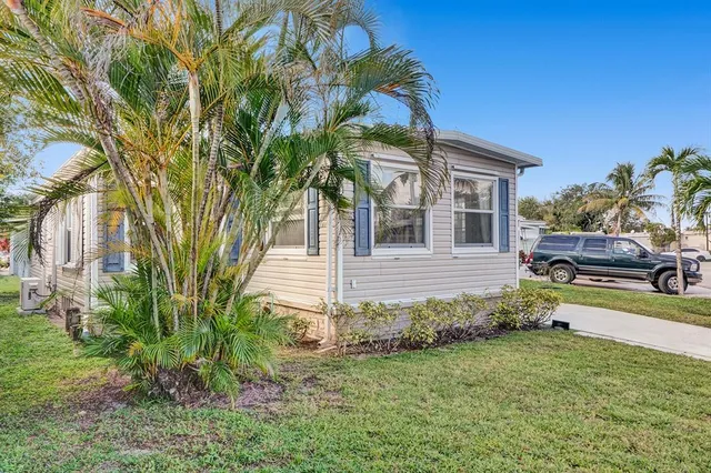 a yellow house with a small yard and large trees