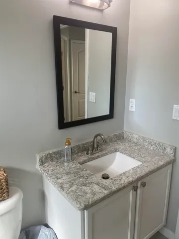 a bathroom with a granite countertop sink and a mirror