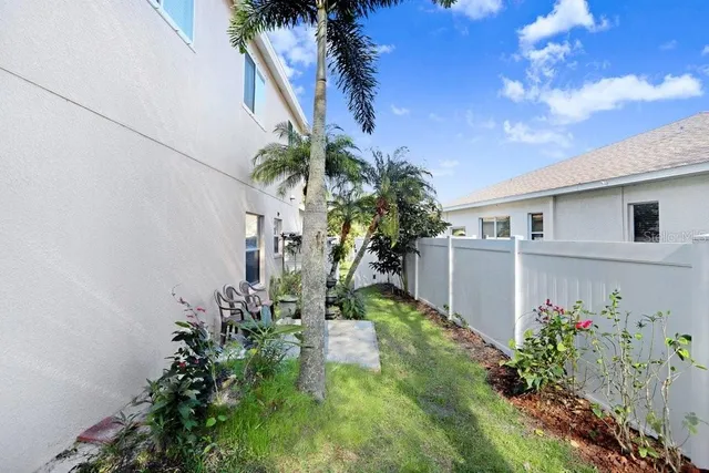 a backyard of a house with table and chairs plants and large tree