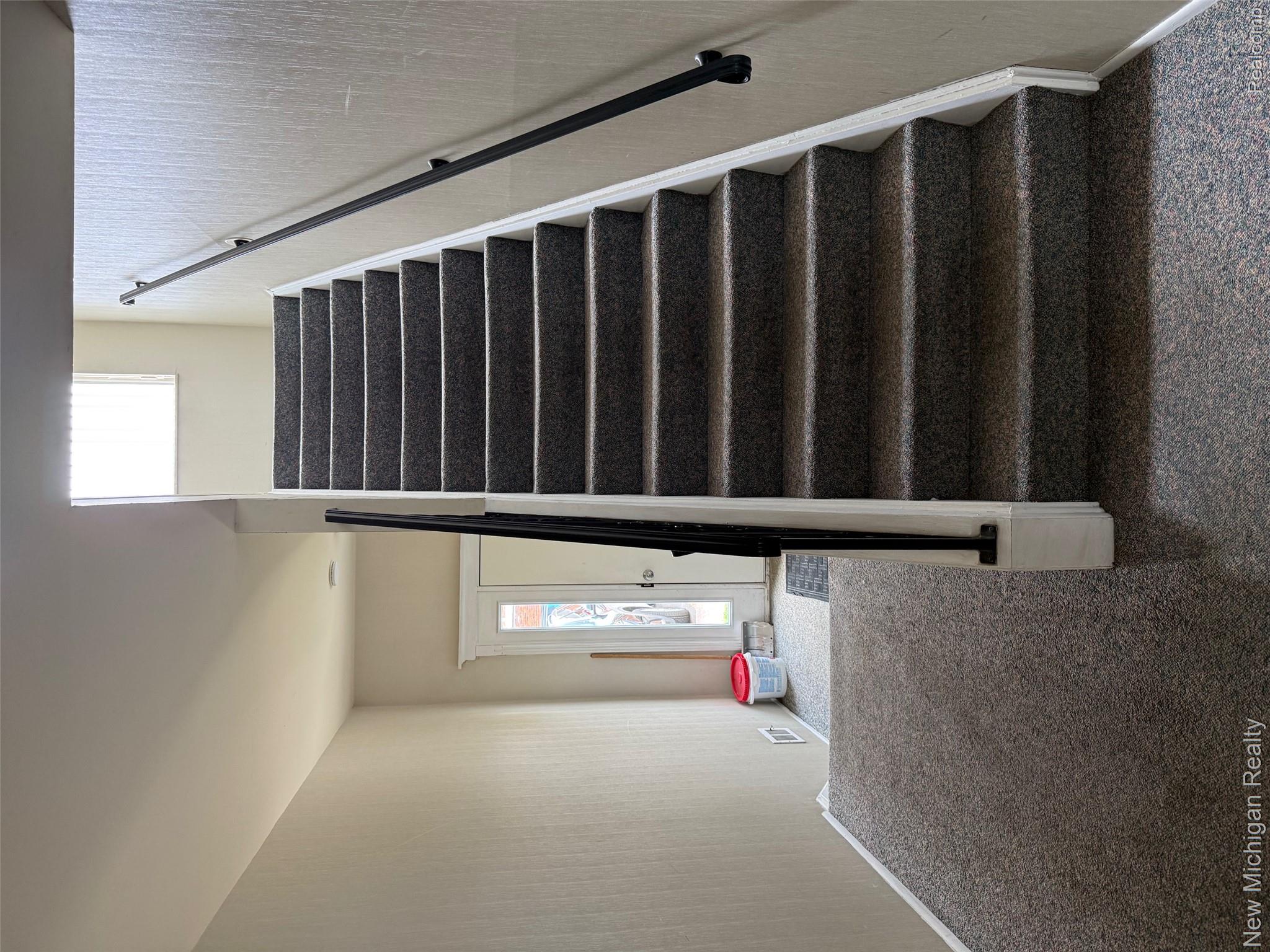 29276 Hoover Road, Unit 276 Warren, MI 48093 - Photo 7 of 14 Carpeted staircase with white risers and a black metal handrail leading to an upper level