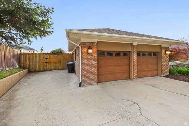 2342 Charros Road Sandy, UT 84092 - Photo 86 of 94 Two-car garage featuring brick facade and wood-finish garage doors with decorative windows